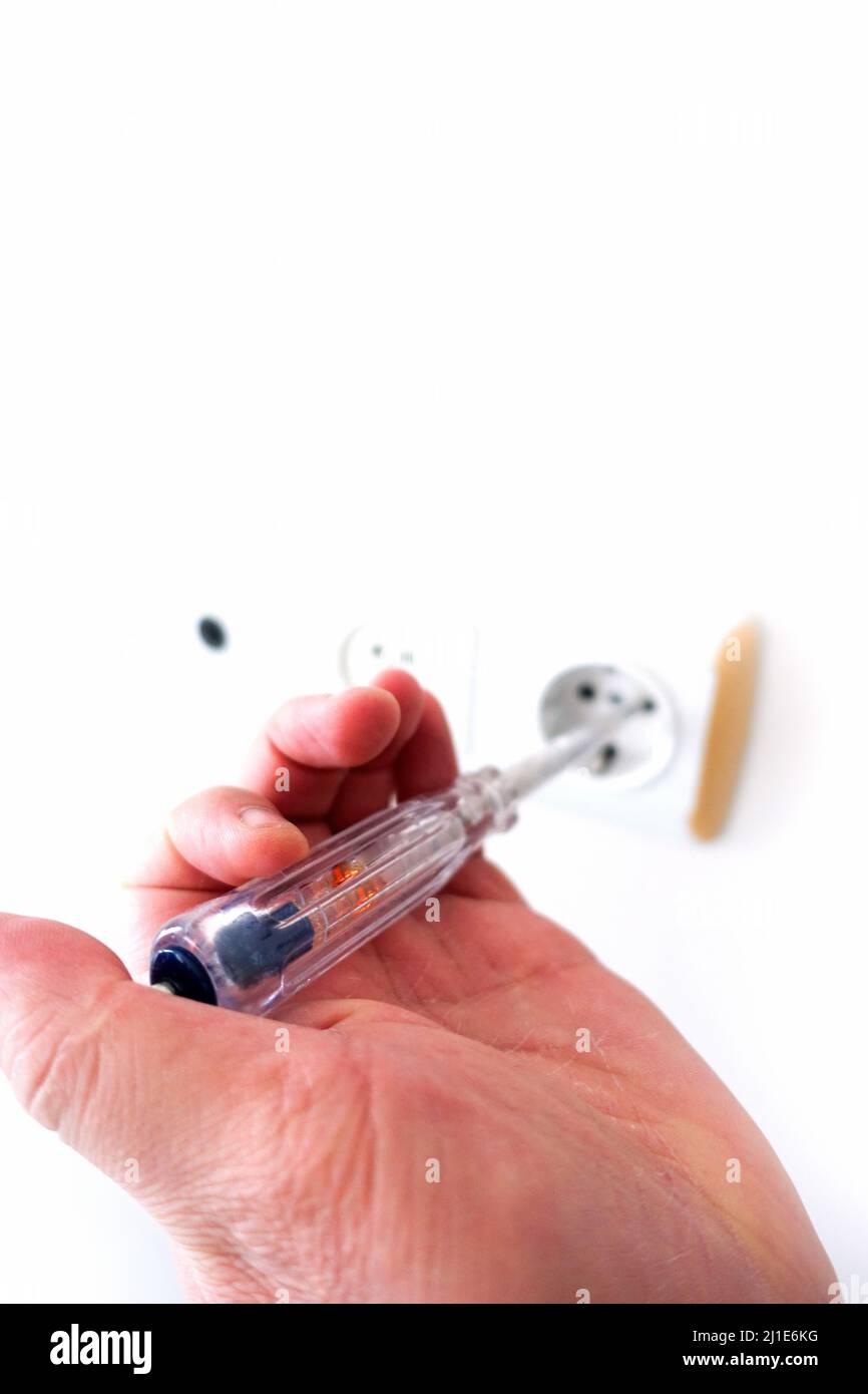 an electrician measuring the electricity in the socket with an electric control pen Stock Photo