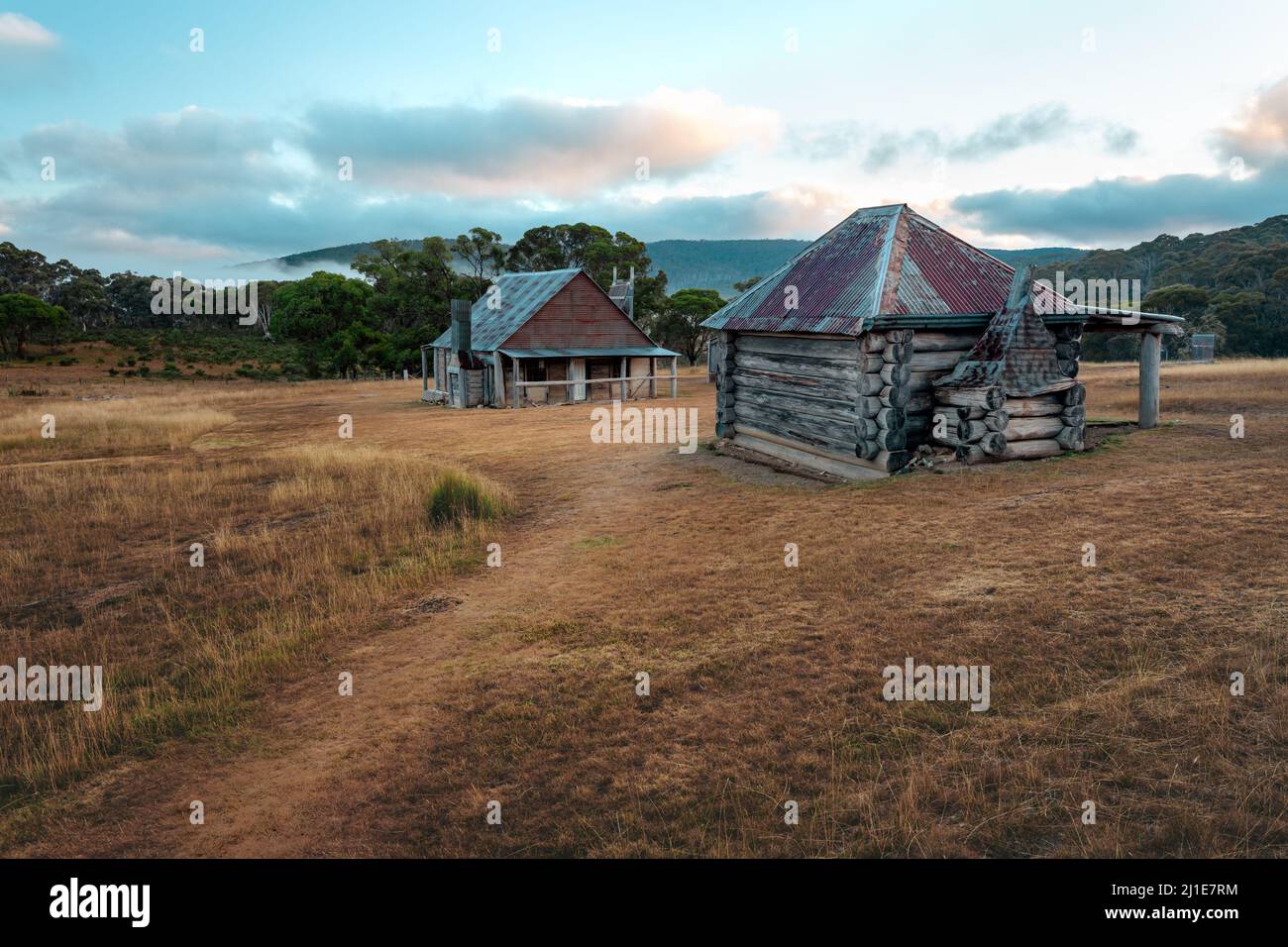 Rustic old log huts sit in a clearing in the high country Stock Photo