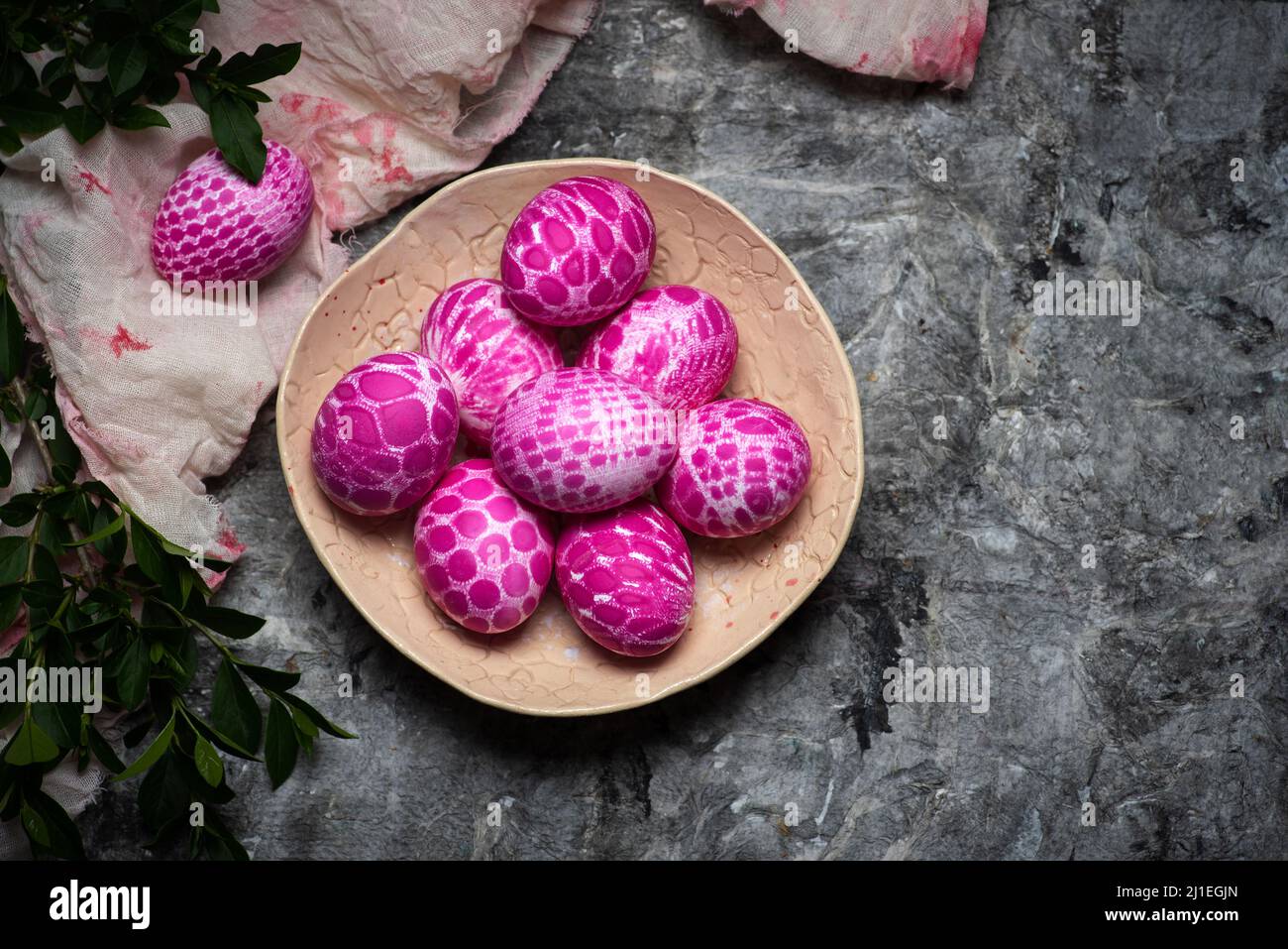 Lace pattern painted pink Easter eggs on a plate on gray background with copy space top view. Easter holiday background Stock Photo