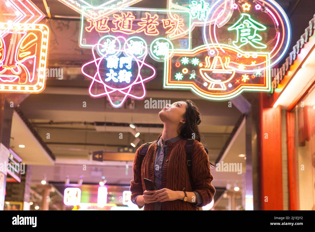 Female white-collar worker looking up at the neon lights - stock photo Stock Photo