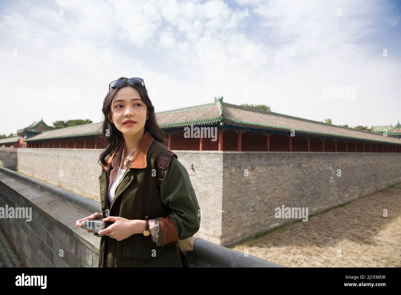 Young woman photographer standing on ancient city wall - stock photo Stock Photo