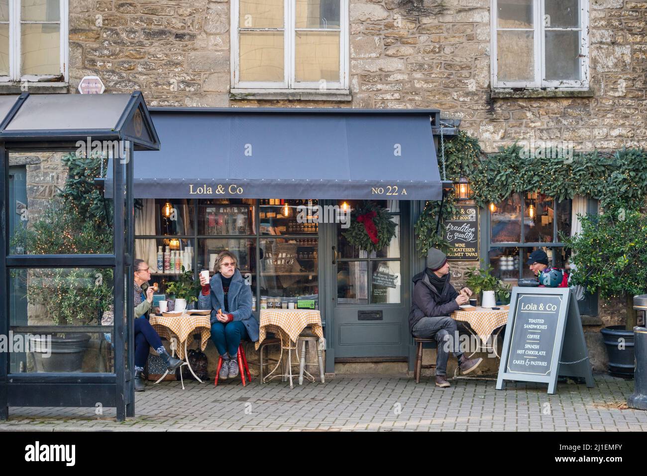 People having coffee outside of cafe during Covid 19 pandemic despite cold weather, Tetbury, Gloucestershire, UK Stock Photo