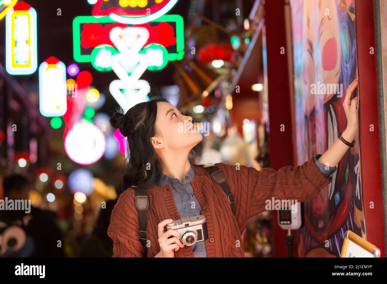 Young female college student admiring art poster at a night market in Beijing - stock photo Stock Photo
