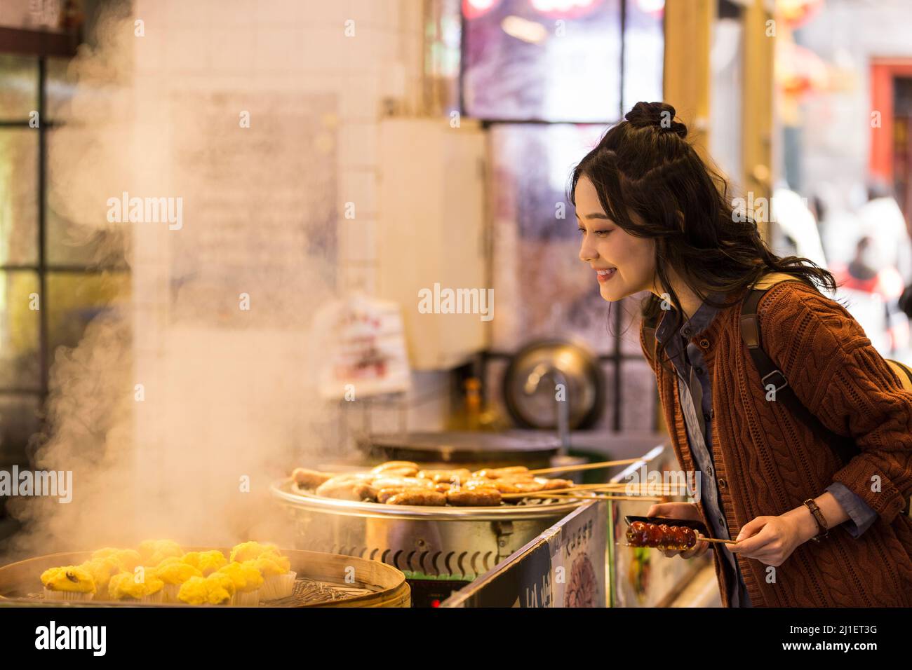 Young Chinese college student selecting steamed rice cakes at a food street in Beijing - stock photo Stock Photo