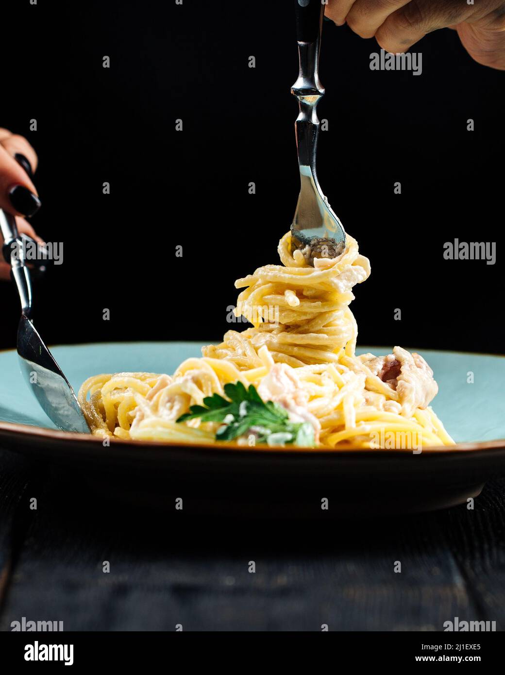 Eating spaghetti carbonara with fork and spoon Stock Photo Alamy