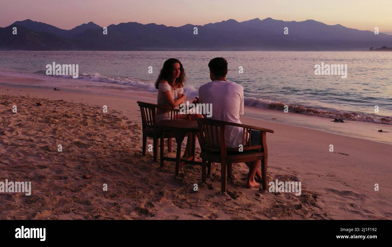 a photo of couple sitting on the beach Stock Photo - Alamy