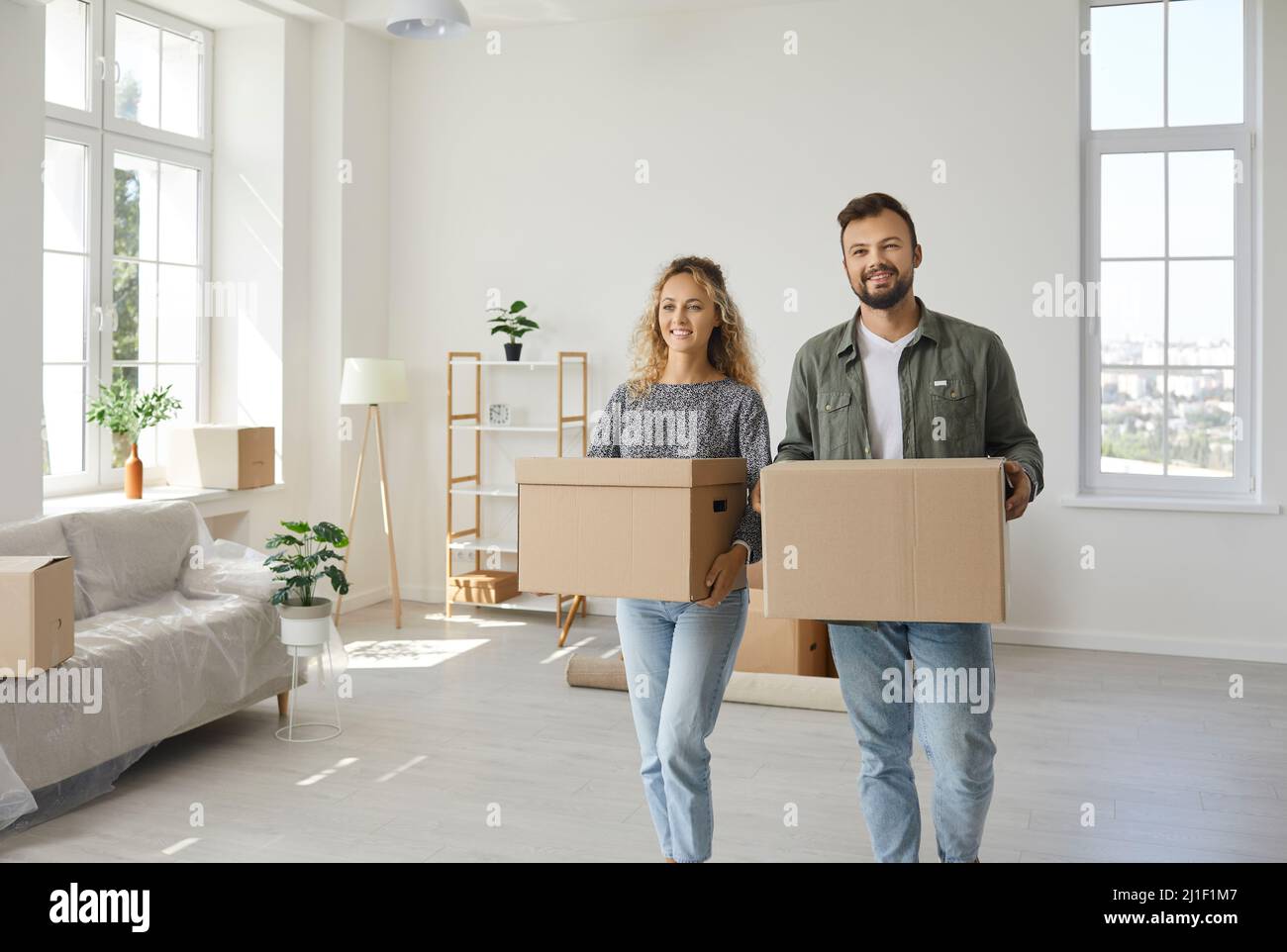 Happy young couple who've moved in a new house carrying some boxes and unpacking stuff Stock Photo