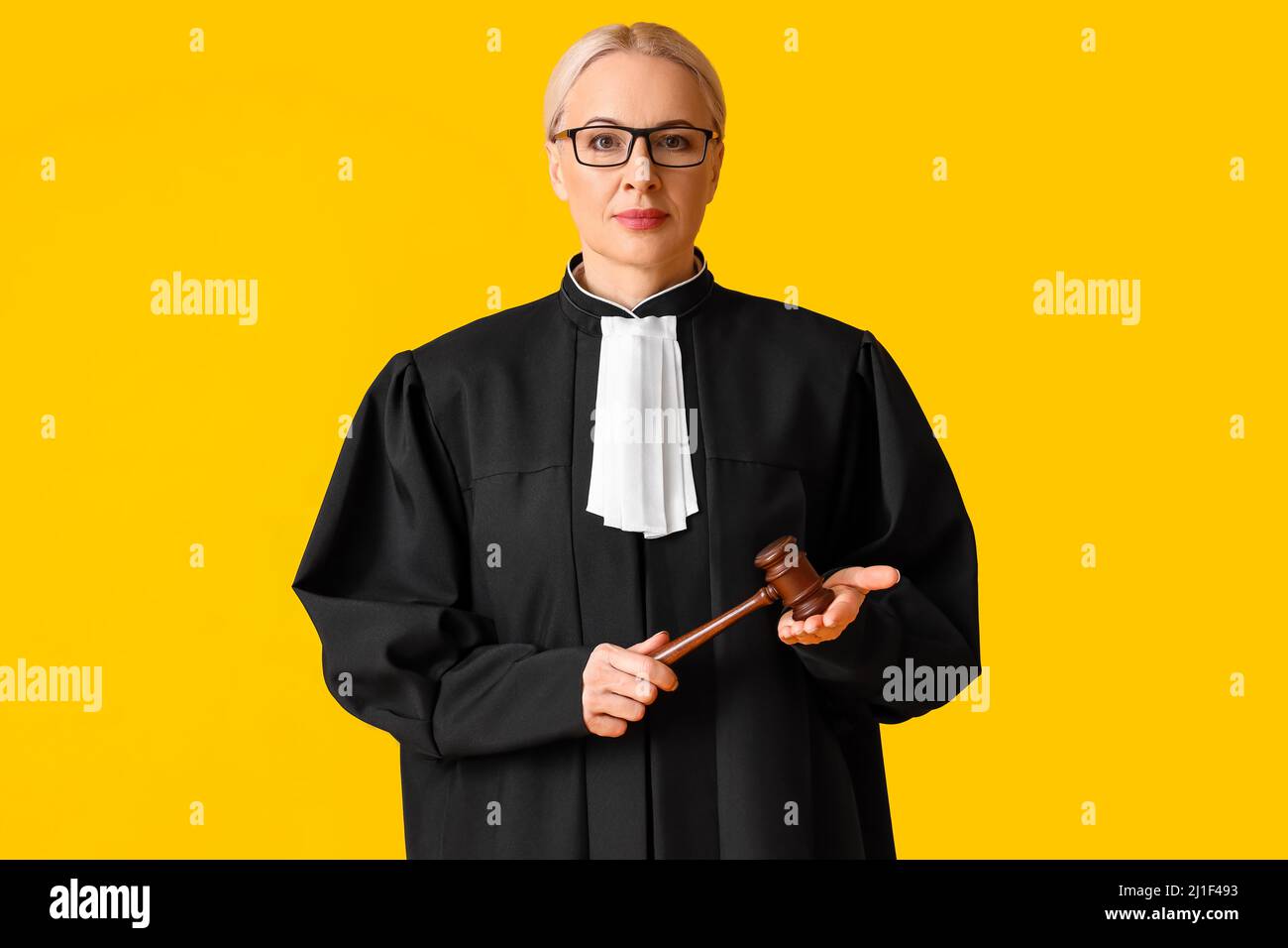 Woman Judge In Robe Mature female judge in robe with gavel on yellow background Stock Photo ...