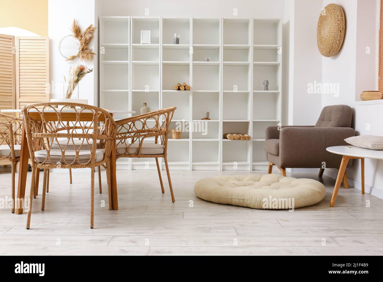 Interior of light dining room with table, shelving unit and armchair ...