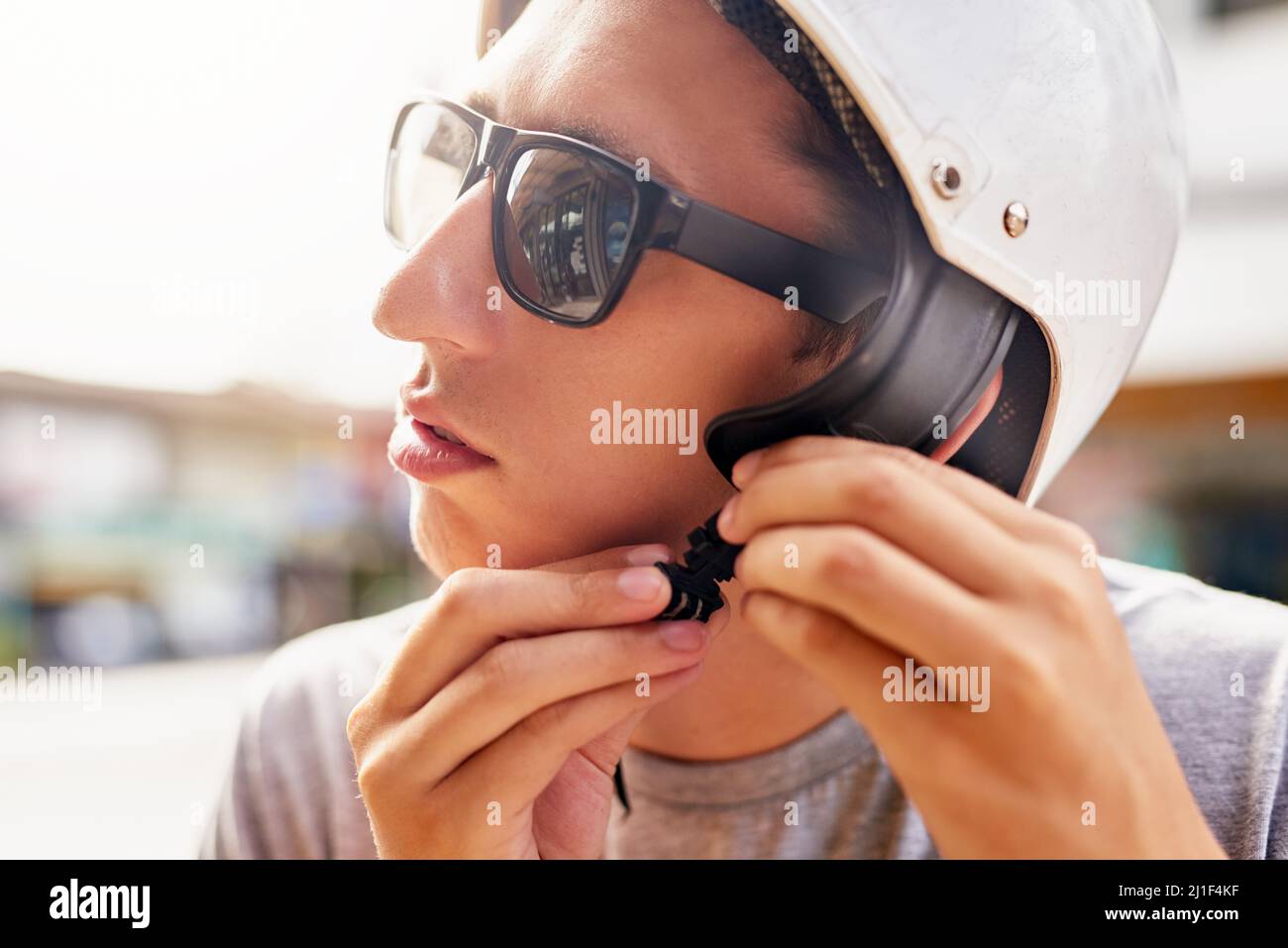 Safety first. Shot of a young man strapping on a bike helmet outside