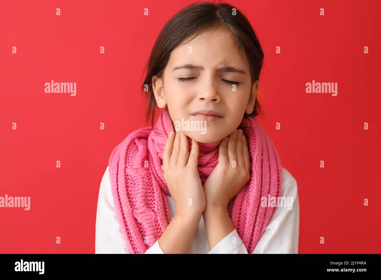 Little girl with scarf suffering from sore throat on red background