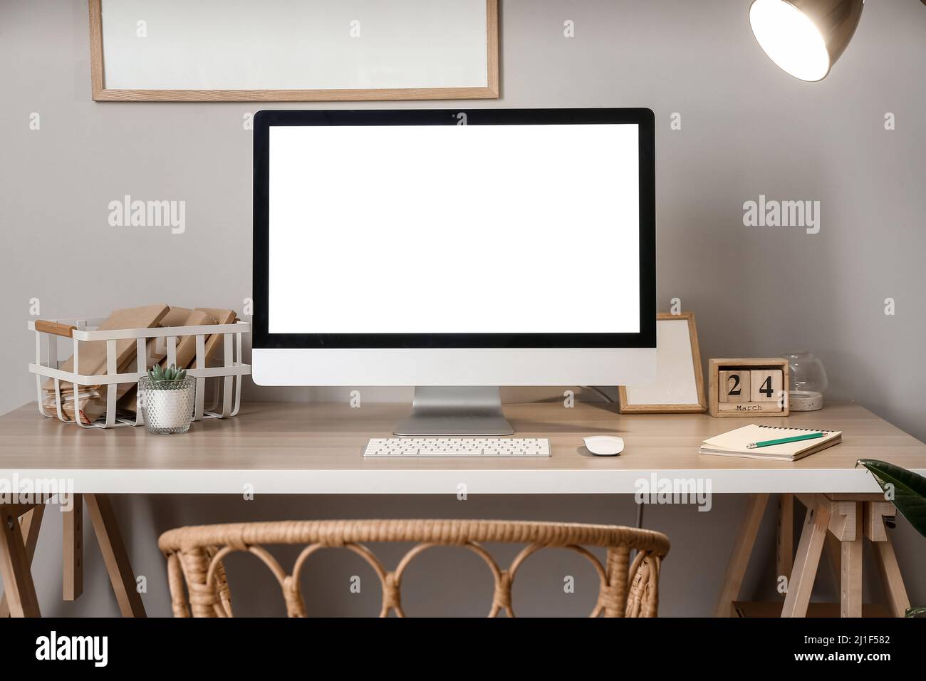 Comfortable workplace with modern computer near grey wall Stock Photo