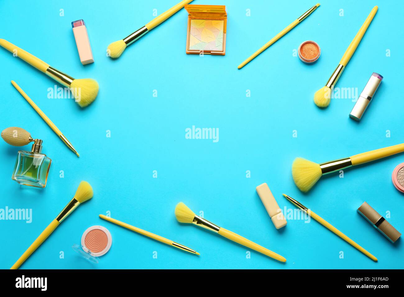 Frame made of makeup brushes and cosmetic products on blue background Stock Photo