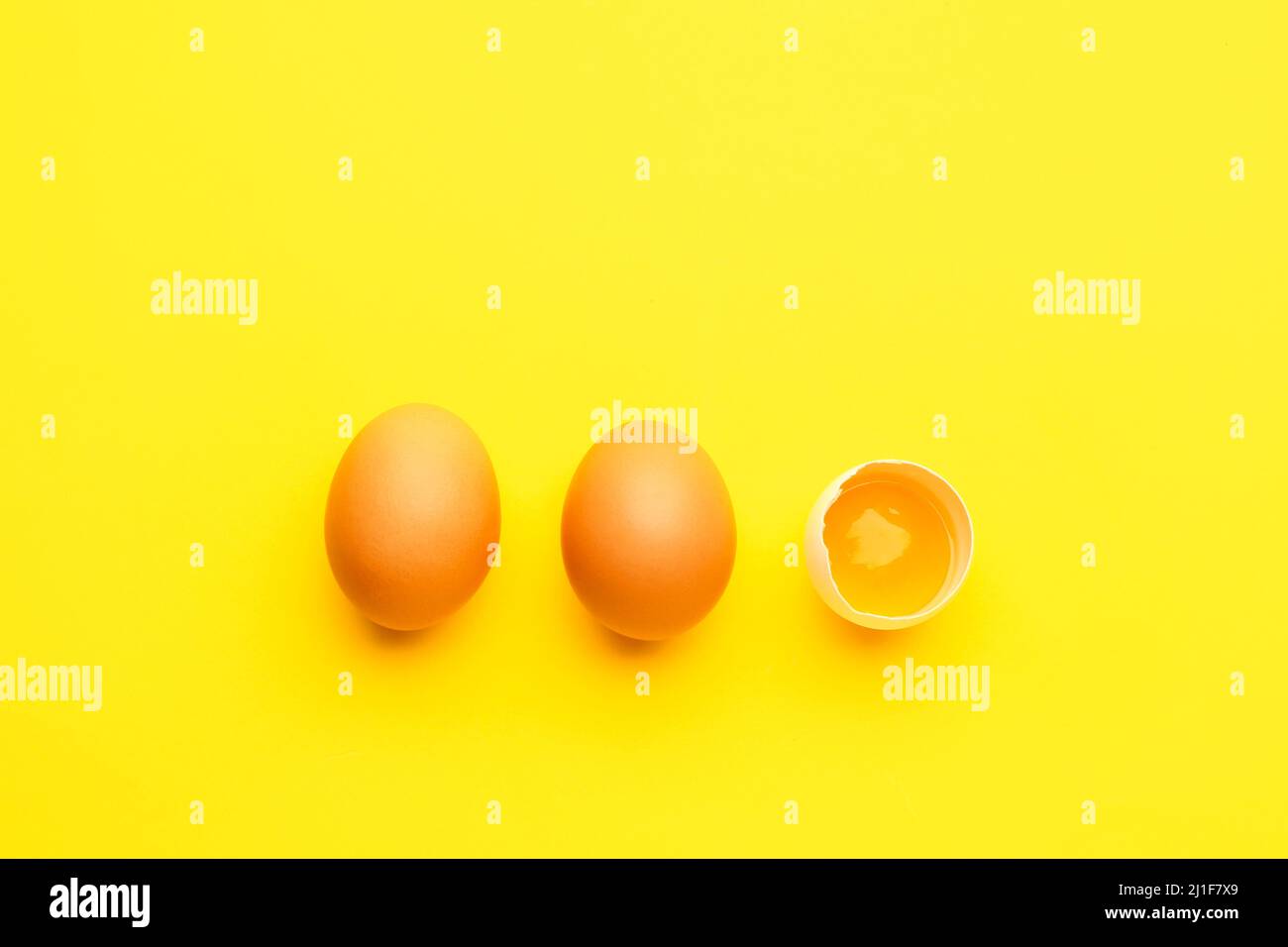 Cracked and whole chicken eggs on yellow background Stock Photo - Alamy