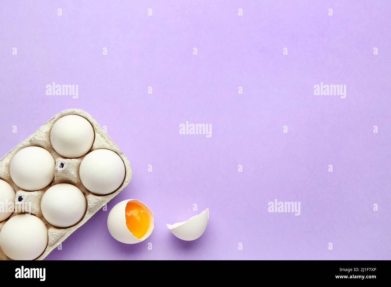 Cracked and whole chicken eggs in holder on purple background Stock ...