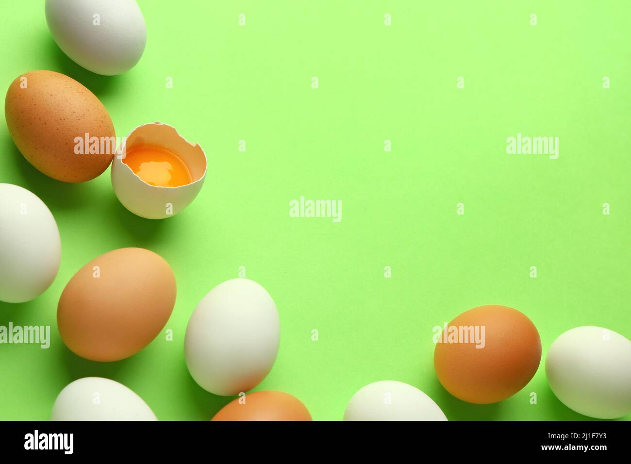 Cracked and whole chicken eggs on green background Stock Photo - Alamy