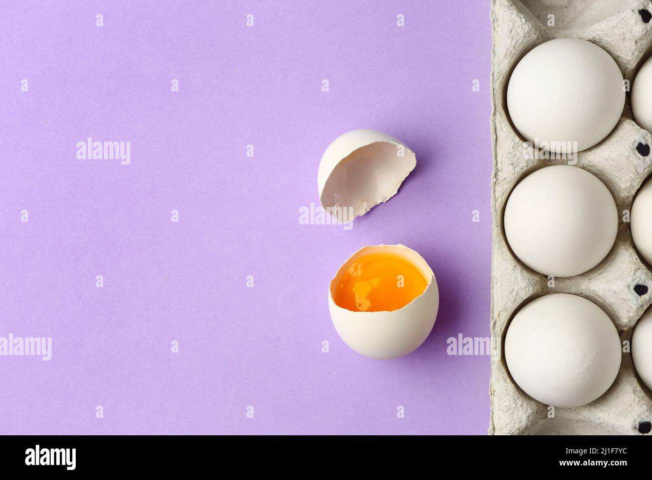 Cracked and whole chicken eggs in holder on purple background Stock ...