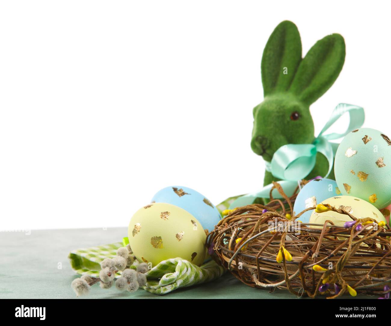 Nest with painted Easter eggs, willow branches and bunny on table ...