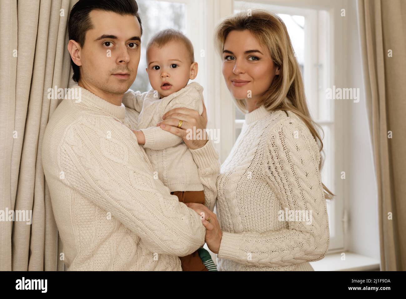 Young and happy family standing beside the window Stock Photo - Alamy