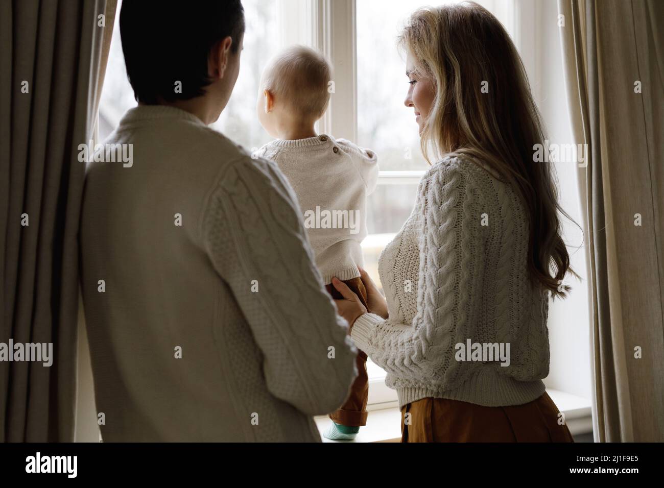 Young family at home is looking out the window Stock Photo