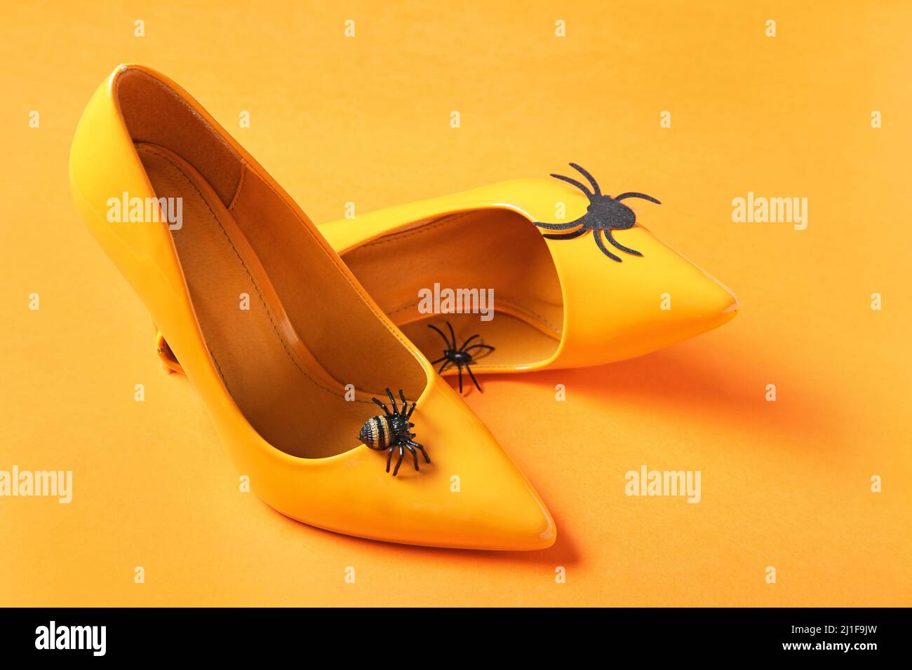 Female shoes with spiders on orange background. April Fool's Day prank
