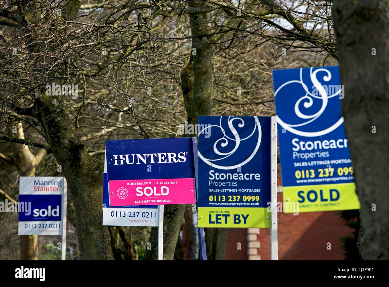 Signs - properties for sale, sold, let and to let - on suburban street, England UK Stock Photo
