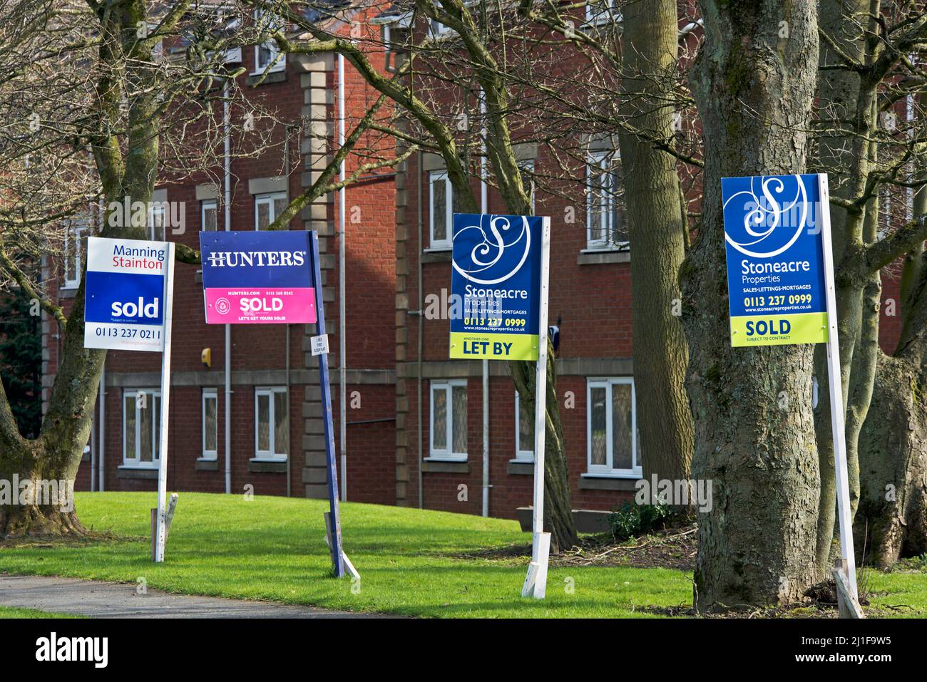 Signs - properties for sale, sold, let and to let - on suburban street, England UK Stock Photo
