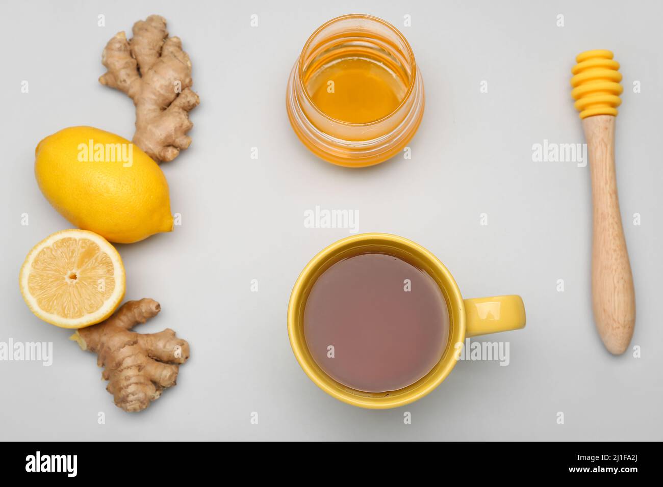 Cup of tea for sore throat, ginger, lemons and honey on light