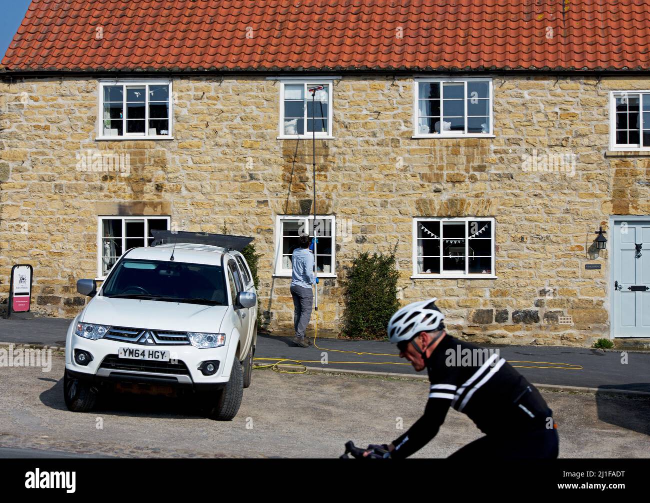 Man cleaning house windows in the village of Coxwold, in Hambleton ...