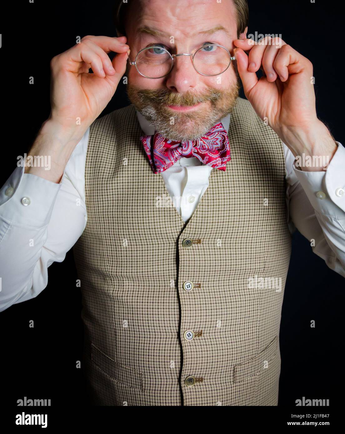 Portrait of Kindly Mature Man in Vest and Bow Tie Adjusting Eyeglasses. Sweet Smiling Gentleman. Stock Photo