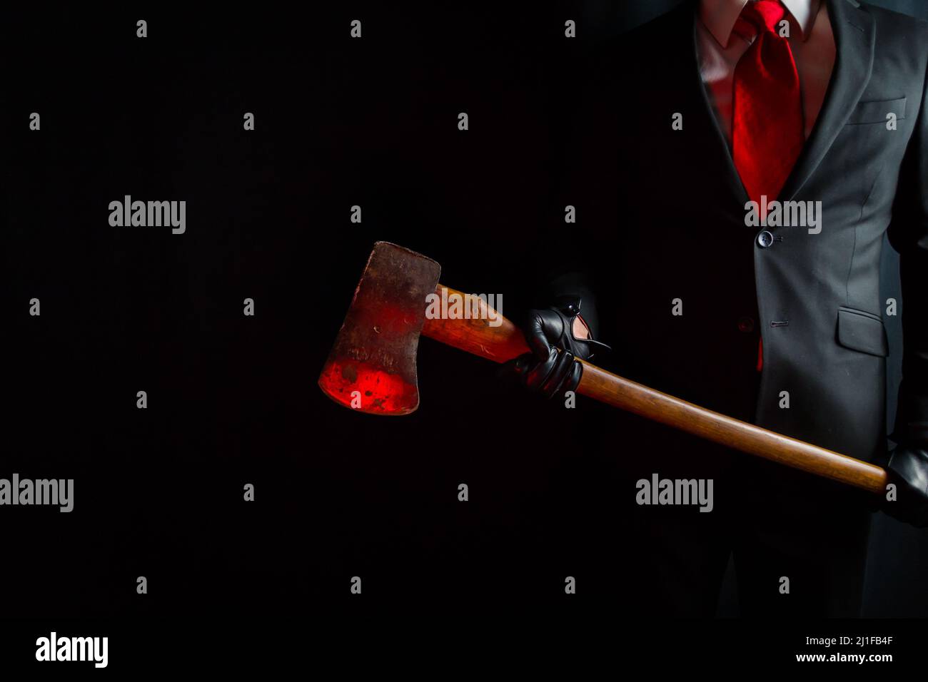 Portrait of Businessman in Dark Suit and Leather Gloves Holding Bloody Red Axe. Concept of Horror Movie Killer. Stock Photo