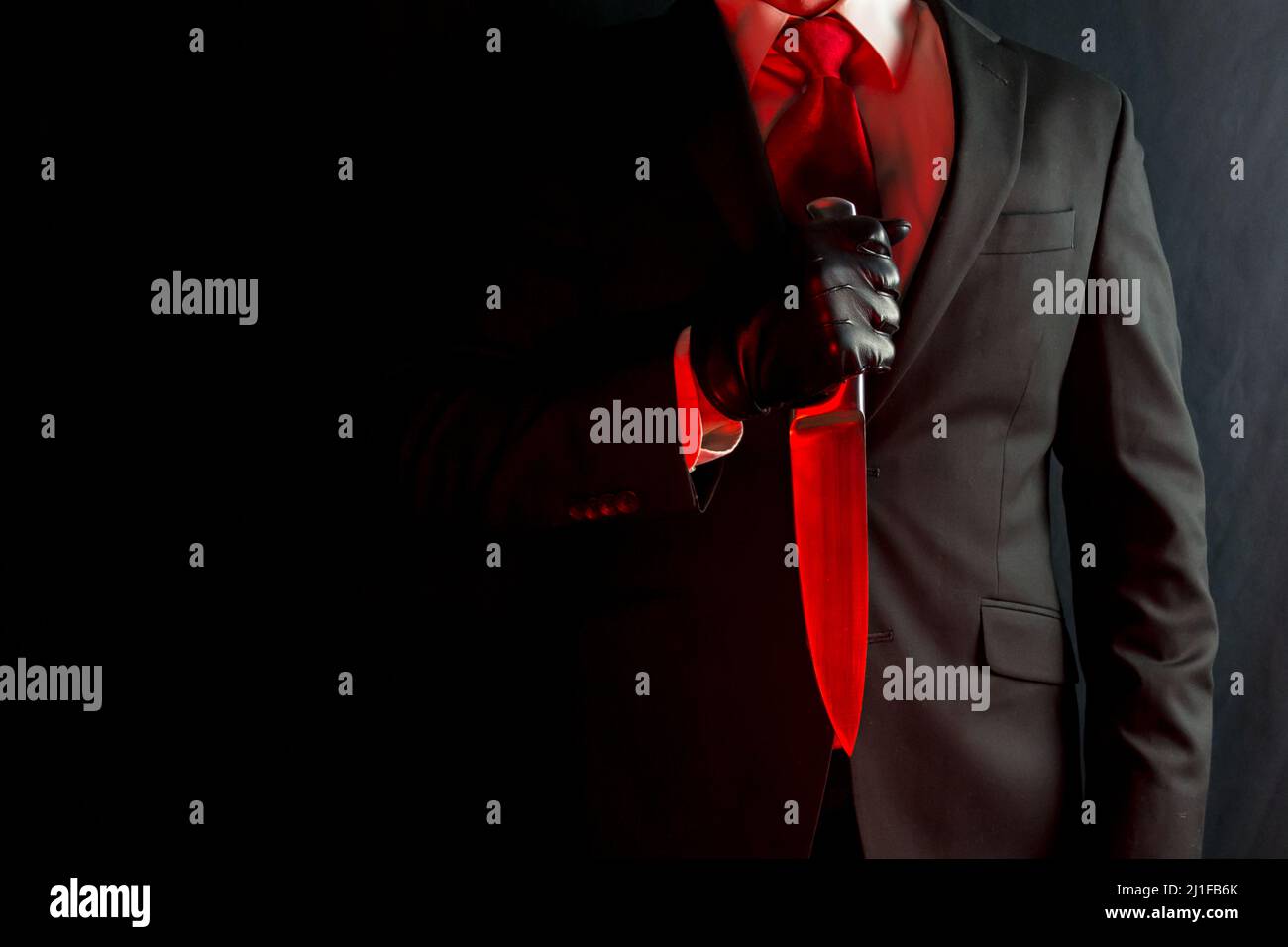 Portrait of Businessman in Dark Suit and Red Tie Holding Sharp Knife. Stylish Assassin and Horror Film Killer. Stock Photo