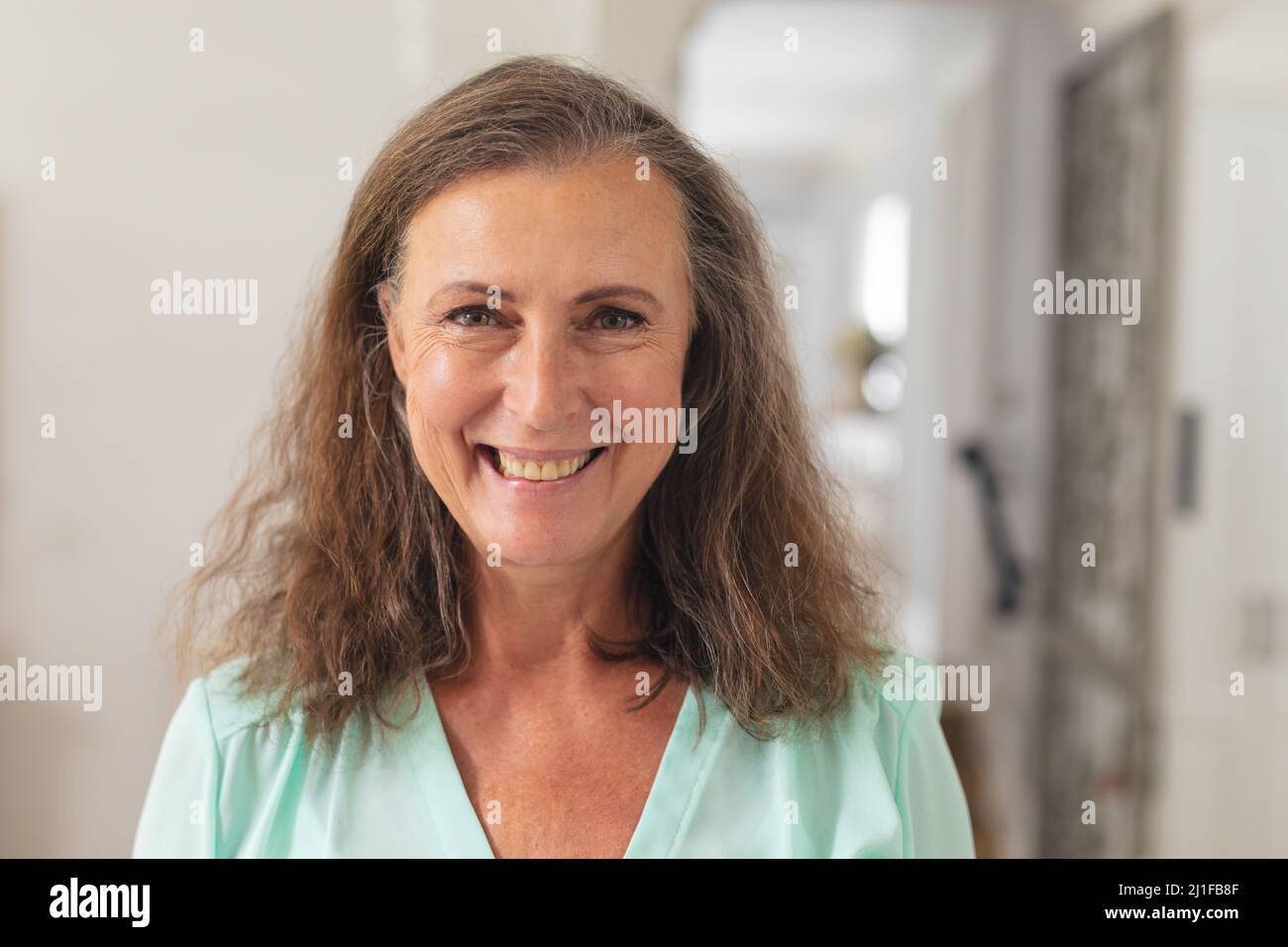 Close-up portrait of happy caucasian senior woman with brown curly hair at home Stock Photo