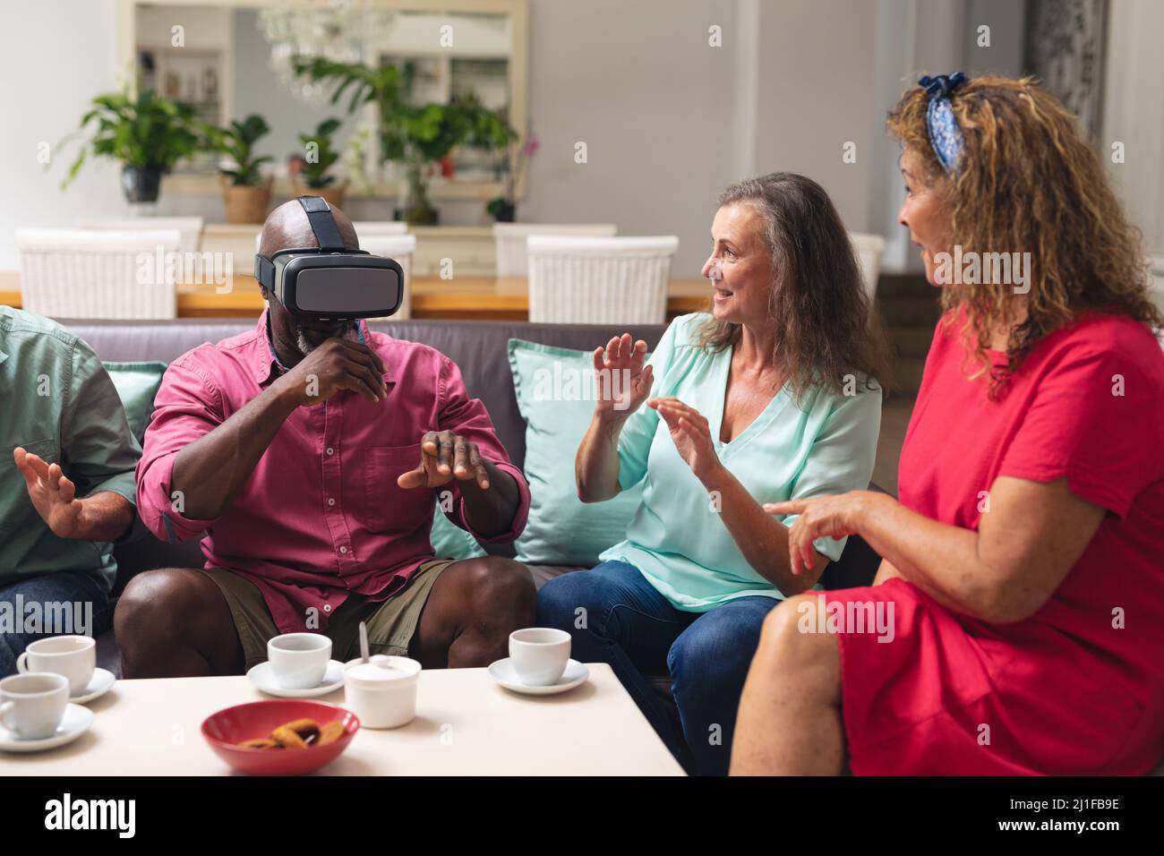 Multiracial senior women and man with male friend using vr headset at home Stock Photo