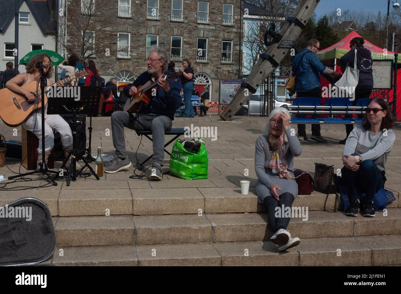 Bantry, West Cork, Ireland, Friday 25 Mar 2022; The sun shone on Bantry Market today drawing people out. Many people where out in t-shirts with tempratures hitting 22 degrees. People enjoying a musical serenade at the weekly market. Credit ED/Alamy Live News Stock Photo