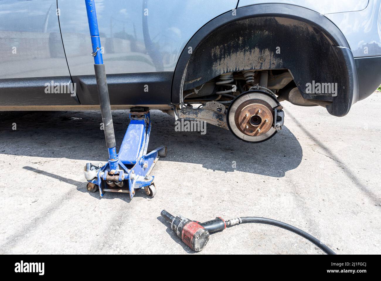 Сar at the tire mounting with removed wheel on pneumatic jack. Seasonal