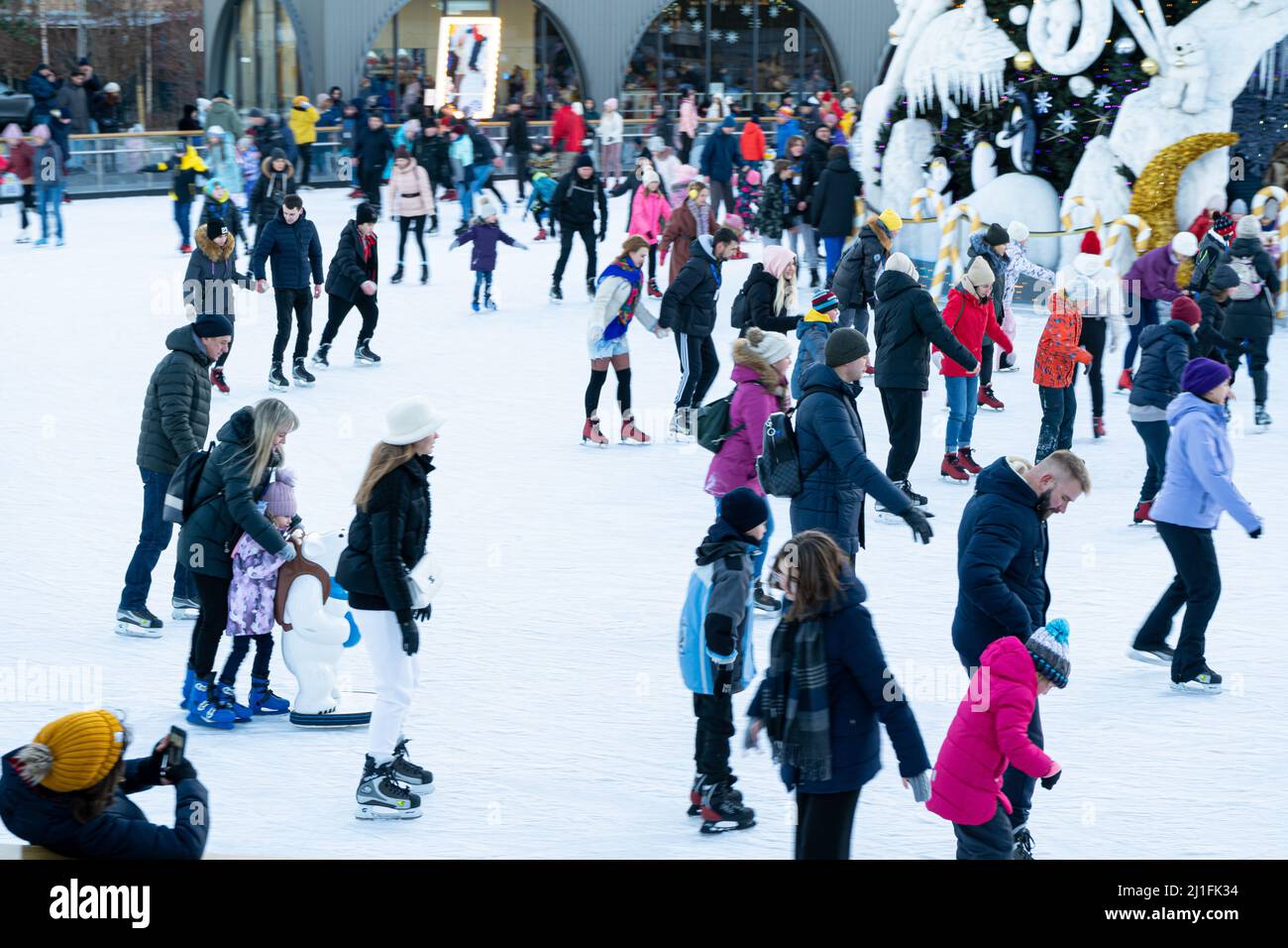 Ukraine, Kyiv - January 7, 2022: Ice skating rink in winter. People are skating. Skates ride on ice. Ice skating is a winter sport entertainment. Christmas time. Christmas tree Roshen factory. Crowd Stock Photo