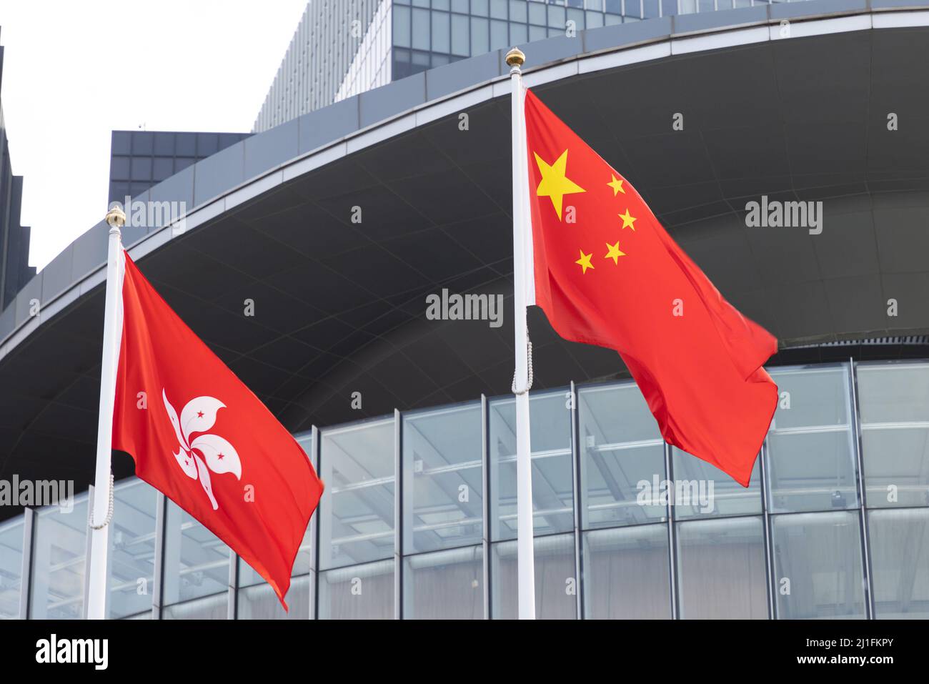 National flag of People’s republic of China and regional flag of Hong Kong Special Administrative region in front of Government Stock Photo