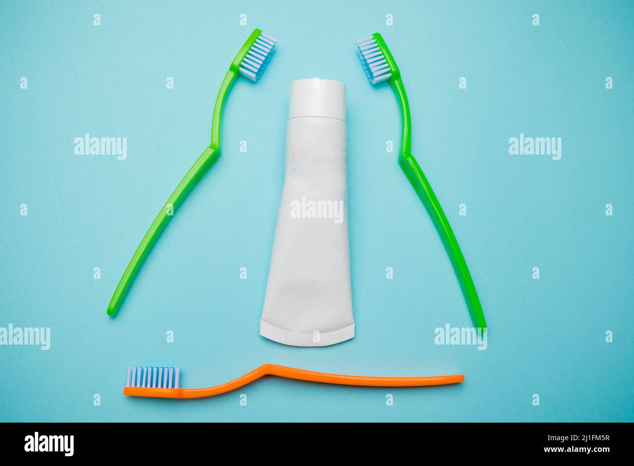 Oral and dental health concept showing three toothbrushes and toothpaste on a blue coloured