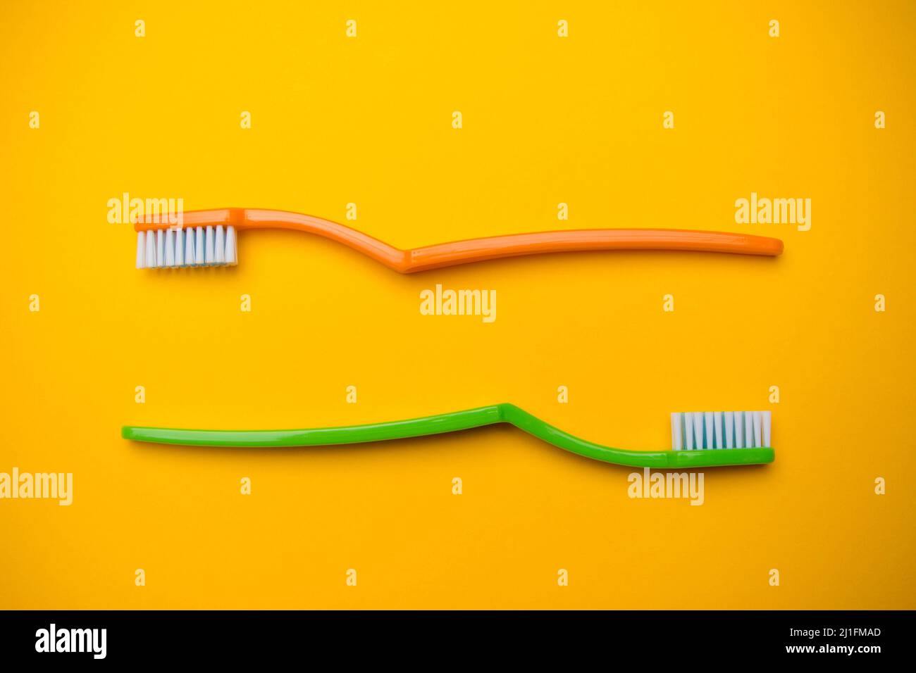Oral and dental health concept showing two toothbrushes on a yellow ...
