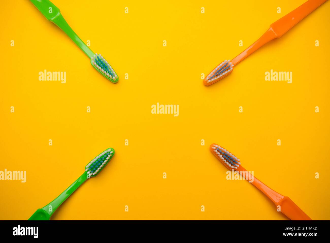 Oral and dental health concept showing four toothbrushes on a yellow ...