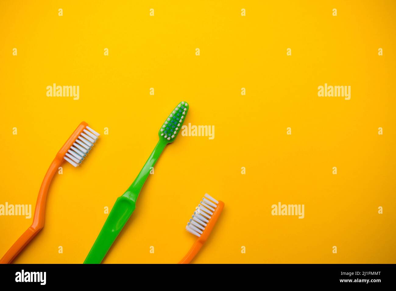 Oral and dental health concept showing three toothbrushes on a yellow ...