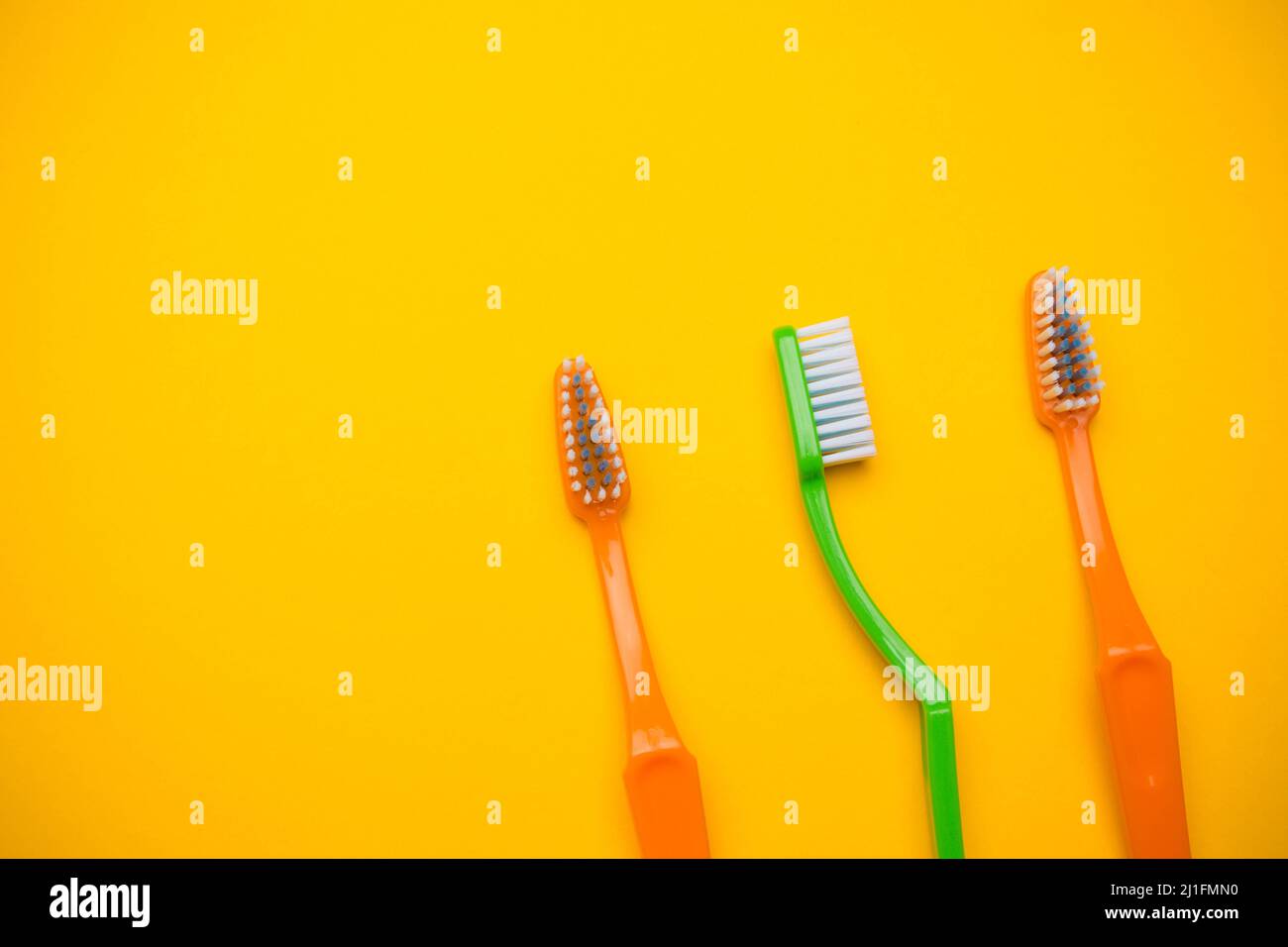 Oral and dental health concept showing three toothbrushes on a yellow ...