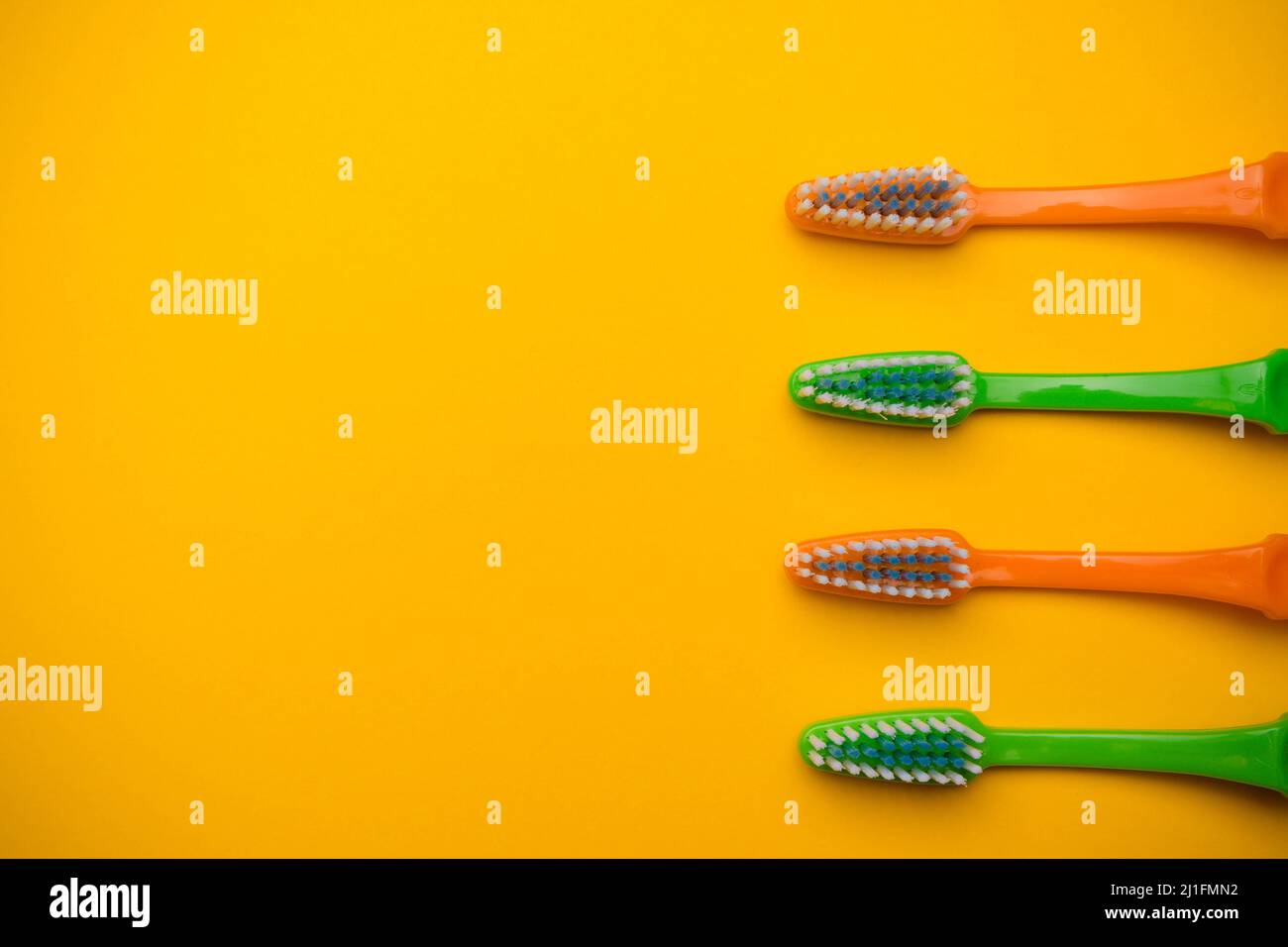 Oral and dental health concept showing four toothbrushes on a yellow ...