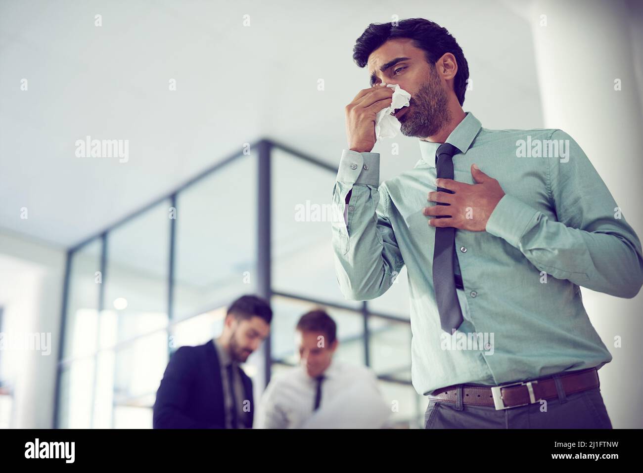 Feeling groggy with flu. Cropped shot of a businessman suffering with allergies in an office. Stock Photo