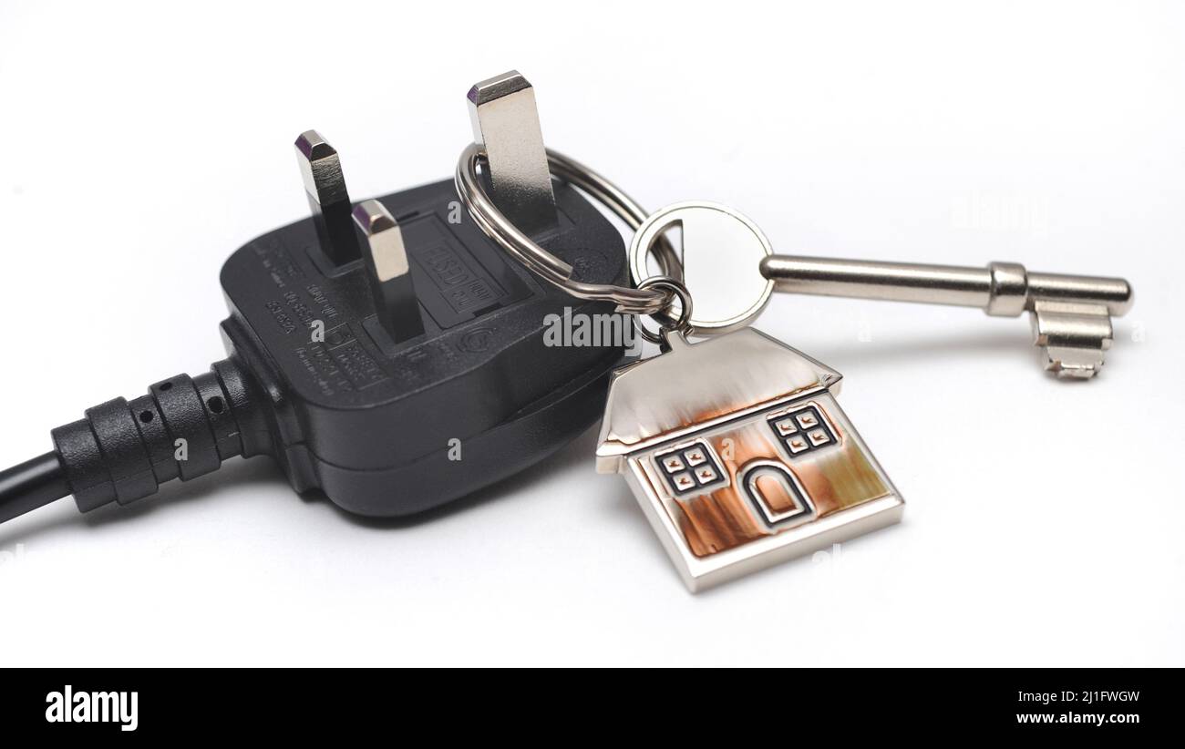 HOUSE KEY AND KEYRING ON DOMESTIC ELECTRIC PLUG RE RISING ELECTRICITY PRICES ENERGY COSTS HOME HEATING POWER ETC UK Stock Photo
