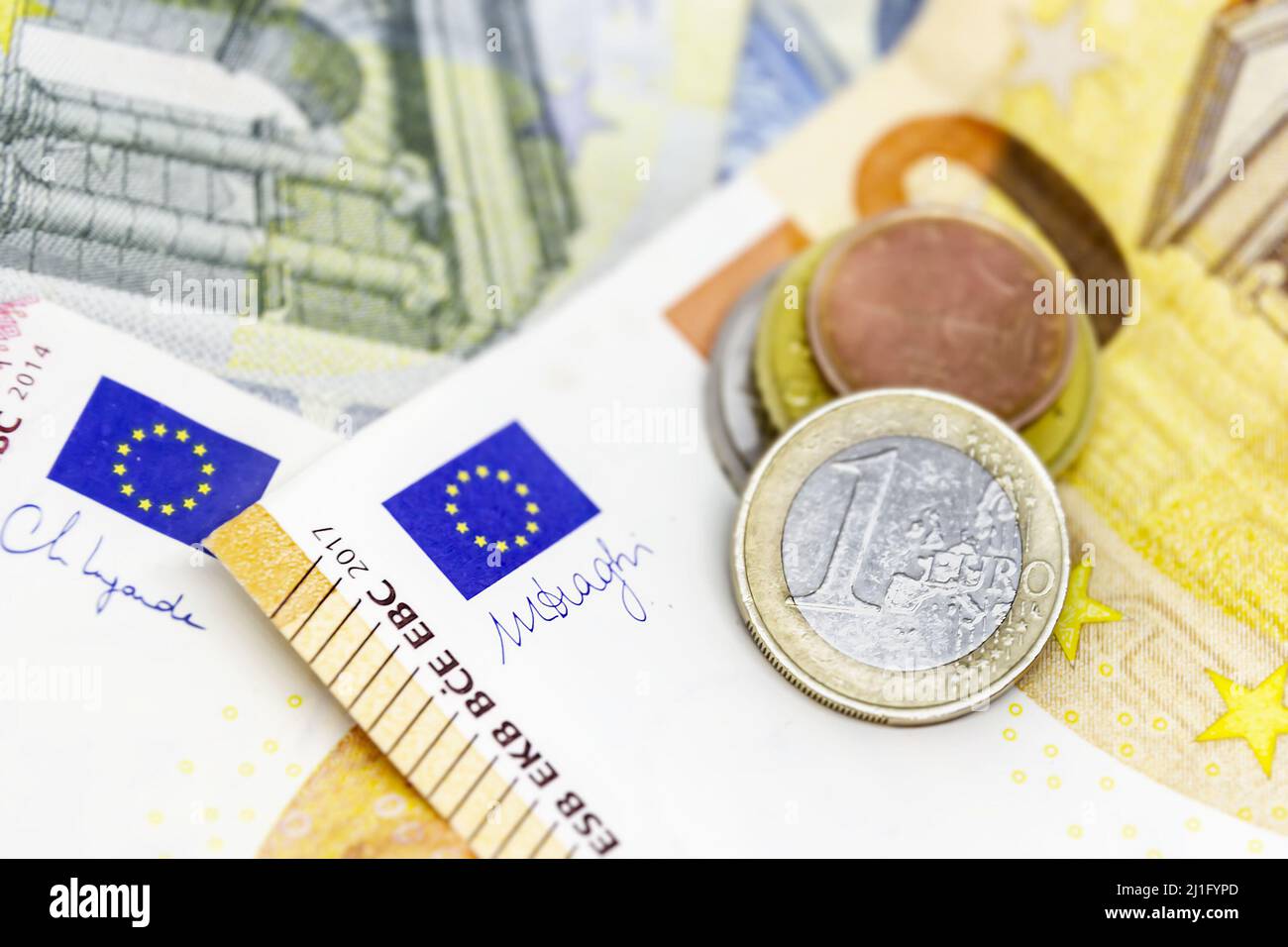One euro coin over some banknotes of different values. The euro is the European currency. Finance, economy and business. Cash and savings Stock Photo