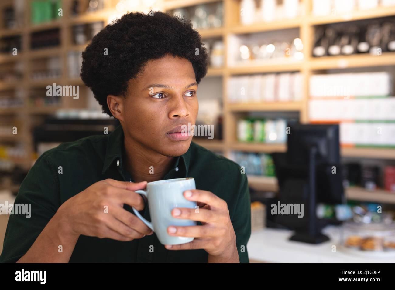 Thoughtful young african american male customer holding coffee mug looking  away in coffee shop. unaltered, cafe culture, people and lifestyle concept  Stock Photo - Alamy