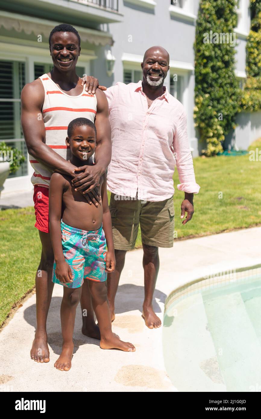 Portrait of happy african american multi-generational family standing at poolside on sunny day Stock Photo