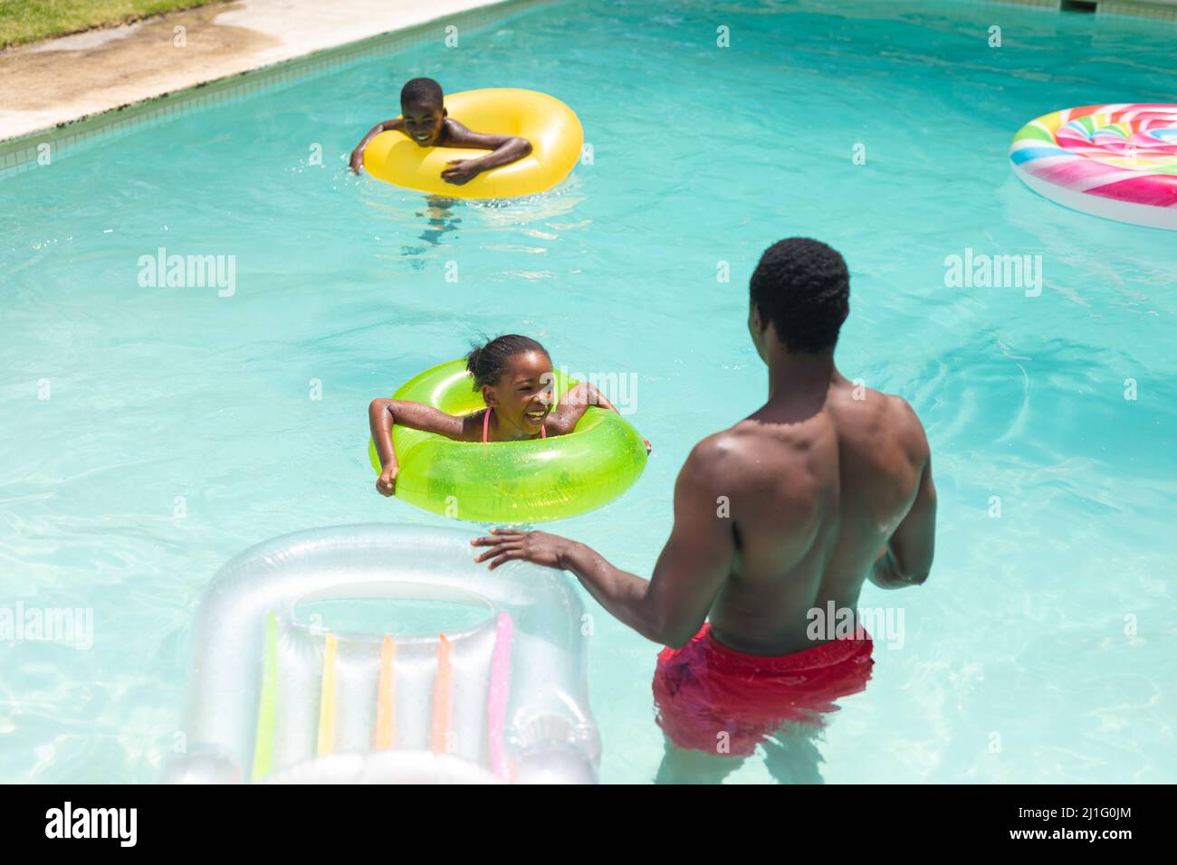 African American Father With Son And Daughter Enjoying Swimming Pool On